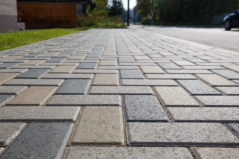 Colorful cobblestone road pavement and lawn divided by a concrete curb. Backlight.