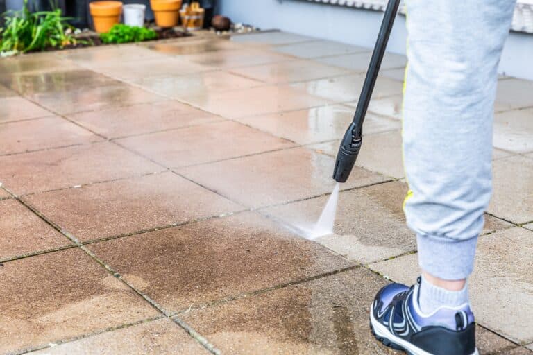 Detail of cleaning terrace with high pressure water blaster, cleaning dirty paving stones